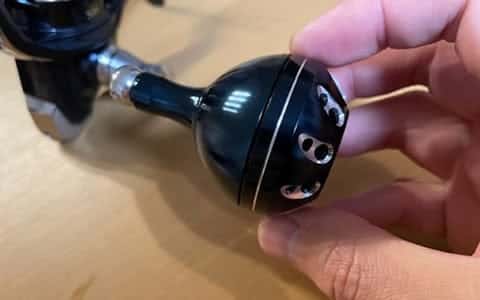 Hand holding a fishing reel part.