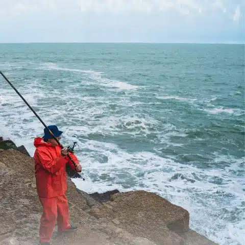 Fisherman casting line by shoreline
