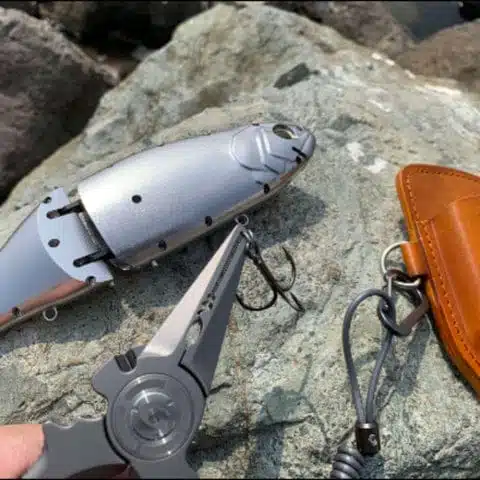 Good Saltwater Fly Fishing Pliers 3 Pliers and lure on stone background.