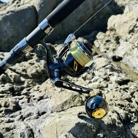 Fishing reel resting on rocky surface.