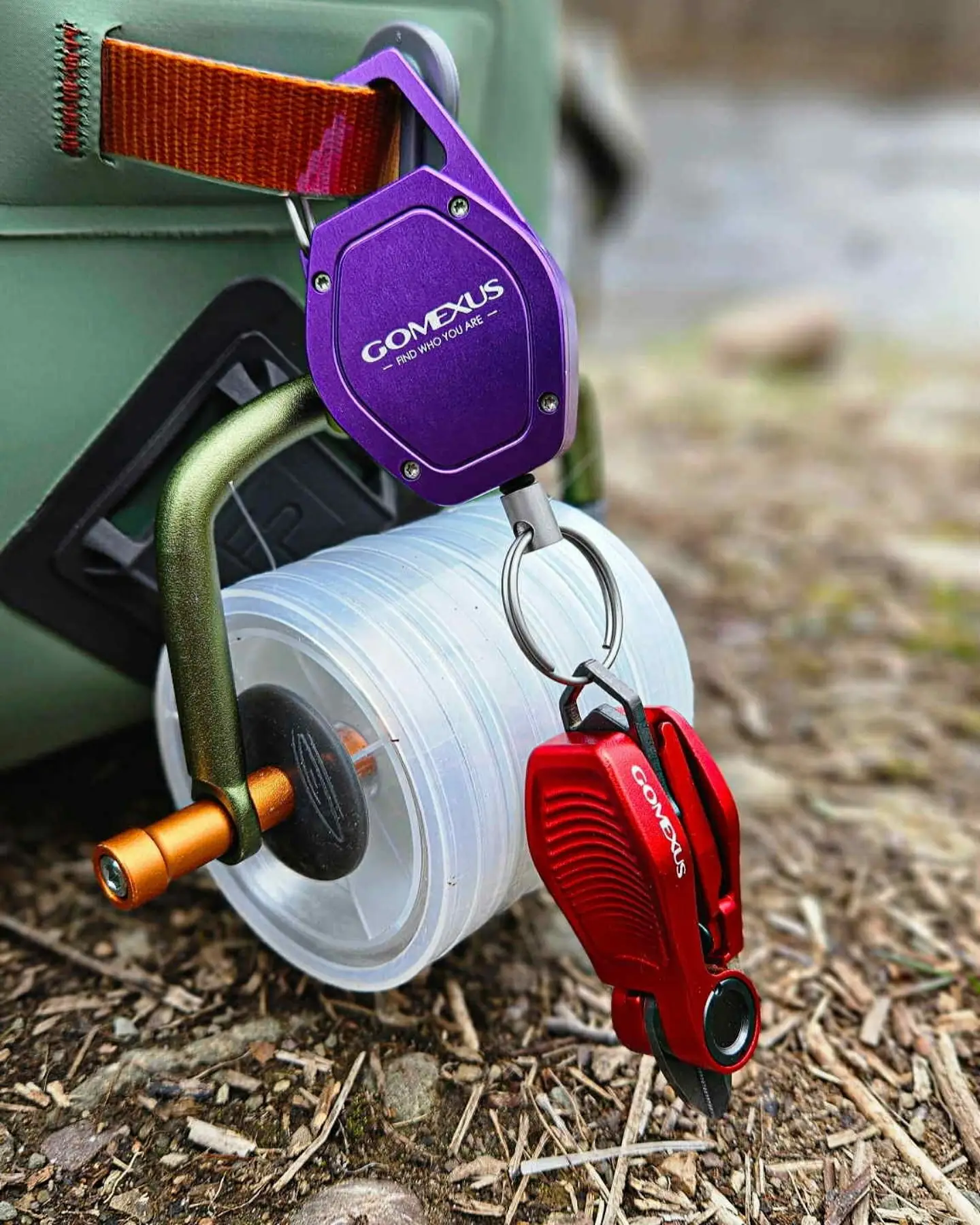 Gomexus-Home 80 Gomexus purple anodized aluminum zinger retractor and red line nipper hanging with a leader spool on a fishing tackle bag