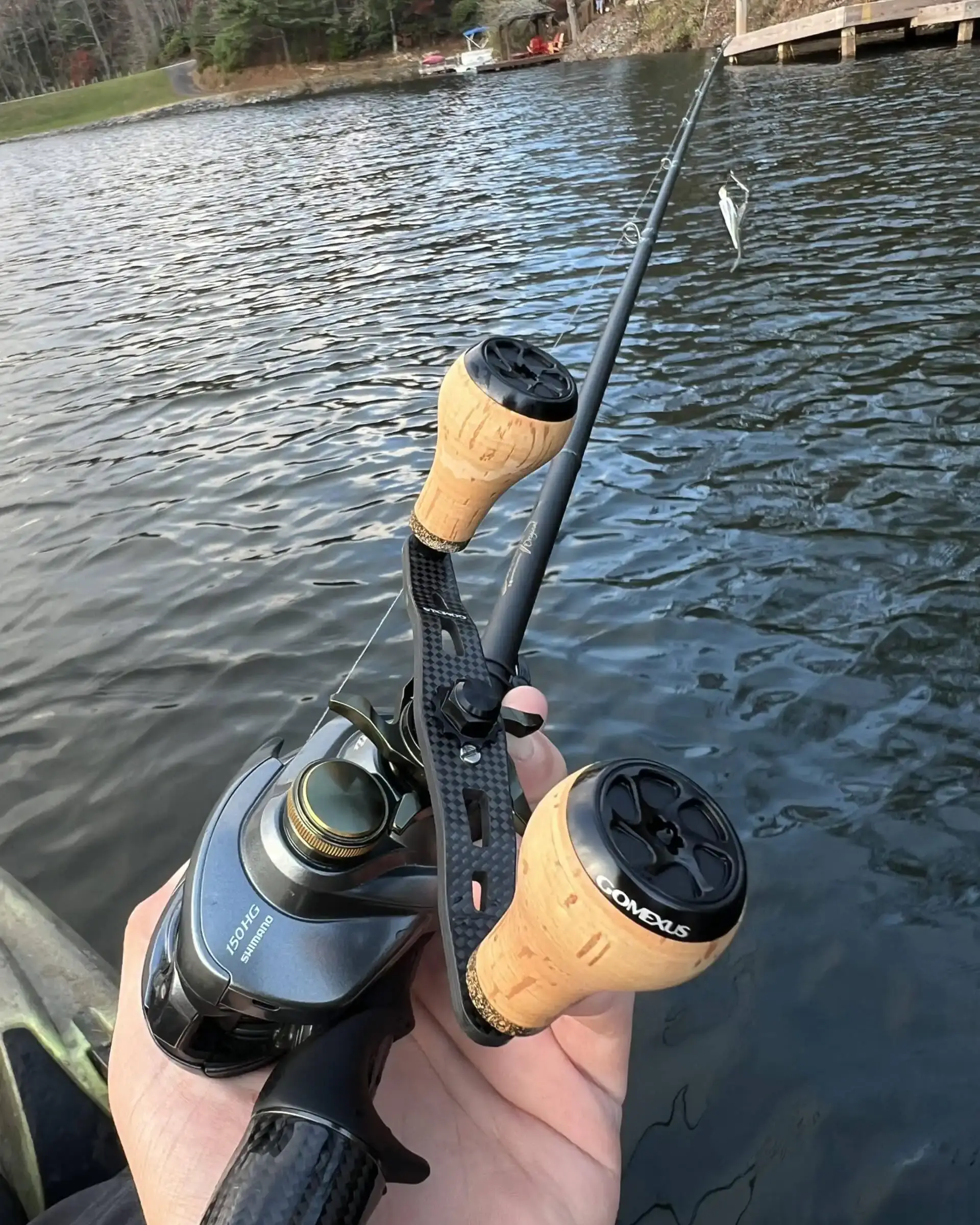 Gomexus-Home 79 Custom Gomexus 3K carbon fiber baitcaster handle with classic cork knobs fitted on a Shimano reel over lake water